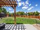 Large backyard with a lush lawn, a wooden fence, and a charming pergola-covered patio area at 2006 E 97Th Ave, Thornton, CO 80229
