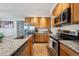 Well-lit kitchen featuring stainless steel appliances, granite countertops, and wood cabinets at 9654 Martin Luther King Jr Blvd, Denver, CO 80238