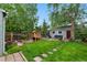 Beautifully landscaped backyard with a playset, fire pit, garden area, and detached garage/shed at 3424 W 31St Ave, Denver, CO 80211