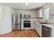 Modern kitchen featuring stainless steel appliances, neutral cabinets, countertop, and hardwood floors at 5441 Lynx St, Frederick, CO 80504