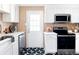 Well-lit kitchen with black and white tiled floors, white cabinets, and stainless steel appliances for modern living at 2313 S Race St # A, Denver, CO 80210