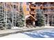 Inviting lodge entrance with wood and stone features, surrounded by snow-covered evergreens and birch trees at 50 Mountain Thunder Dr # 1212, Breckenridge, CO 80424
