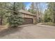 Long paved driveway leading to a two-car garage with stone and tudor accents at 150 Soda Creek Rd, Evergreen, CO 80439