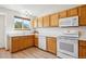 Modern kitchen with white countertops, wood cabinets, and sleek white appliances at 9652 Cove Creek Dr, Highlands Ranch, CO 80129
