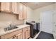 Well-lit laundry room features modern washer and dryer, tile floor, and wooden cabinets with sink at 940 Kearney St, Denver, CO 80220