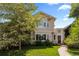 Charming stucco two-story home with arched porch, flowering tree, and landscaped yard at 1172 S Steele St, Denver, CO 80210
