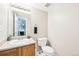 Clean bathroom featuring a toilet, sink and large mirror, with a glimpse into the laundry room at 13036 W Cross Dr, Littleton, CO 80127