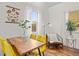 Bright dining area with hardwood floors, yellow chairs, and a charming window view of the outdoors at 936 Utica St, Denver, CO 80204