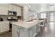 Open kitchen with white cabinets, quartz counters, island seating, and stainless steel appliances at 9612 Reunion Pkwy, Commerce City, CO 80022