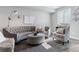 Bright living room featuring a gray tufted sofa, ottoman, and plush chair under natural light at 9612 Reunion Pkwy, Commerce City, CO 80022