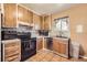 Cozy kitchen featuring wooden cabinetry, black appliances, and a window above the sink at 11816 Spring Dr, Northglenn, CO 80233