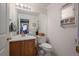Cozy half bathroom featuring oak vanity, white countertop, and framed mirror with decorative wall storage at 22379 E Dorado Ave, Aurora, CO 80015