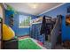 Blue bedroom with a loft bed, bright green rug, and a window with a view of green trees at 22379 E Dorado Ave, Aurora, CO 80015