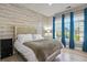 Comfortable bedroom with wood-look accent wall, plush bedding, and a bright window with blue curtains at 5677 S Park Pl # 303, Englewood, CO 80111