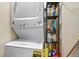 Efficient laundry area with stacked washer and dryer unit, alongside shelving for storage of cleaning supplies at 5677 S Park Pl # 303, Englewood, CO 80111
