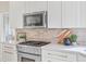 Bright kitchen with stainless appliances, brick backsplash, and white cabinets at 31699 Southern Hills Pl, Evergreen, CO 80439