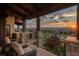 An outdoor patio space with dark wicker furniture, stone pillars, and a view of the distant mountains at 10805 Evergold Way, Highlands Ranch, CO 80126