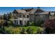 Expansive home exterior with stone accents, large windows, covered patios, and lush landscaping at 10805 Evergold Way, Highlands Ranch, CO 80126