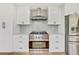 Bright kitchen with stainless steel gas range and hood, stylish cabinets, and tile backsplash at 2122 S Zephyr St, Lakewood, CO 80227