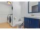 Well-lit bathroom featuring a blue vanity, toilet, and a modern washer and dryer for added convenience at 4935 Apollo Bay Dr, Highlands Ranch, CO 80130