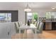 Staged dining area featuring a white table, six chairs, modern lighting, and backyard access at 4935 Apollo Bay Dr, Highlands Ranch, CO 80130