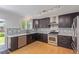 Well-lit kitchen featuring dark cabinetry, stainless steel appliances, mosaic backsplash, and wood flooring at 4935 Apollo Bay Dr, Highlands Ranch, CO 80130