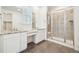 Bathroom featuring a dual vanity with granite counters, large mirrors, and a glass enclosed shower at 5128 Preserve Pl, Firestone, CO 80504