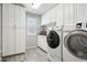 Well-organized laundry room with modern washer and dryer, white cabinets, and gray wood floors at 10889 Alcott Ct, Denver, CO 80234
