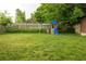 Spacious backyard featuring green grass, a wooden fence, mature trees and a playset at 654 S Shoshone St, Denver, CO 80223