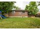 Large green backyard featuring a brick home, small patio, wooden fence and playset at 654 S Shoshone St, Denver, CO 80223