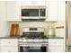 Modern kitchen with stainless steel stove and microwave, white cabinets, and dark countertops at 654 S Shoshone St, Denver, CO 80223