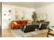 Inviting living room featuring an orange sofa, stylish decor, and a light gray rug on wood flooring at 654 S Shoshone St, Denver, CO 80223