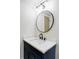 Bathroom vanity with white marble countertop, black faucet and dark blue cabinets with gold hardware at 3100 S Holly Pl, Denver, CO 80222