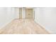 Hallway with light wood floors, white base trim, and two tan doors at the end at 3100 S Holly Pl, Denver, CO 80222
