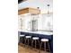 Modern kitchen featuring white cabinets, stainless steel appliances, and a navy blue island with bar stools at 3100 S Holly Pl, Denver, CO 80222