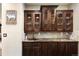 Close up of dry bar area with granite countertops, custom cabinetry, tile backsplash, and copper sink and fixtures at 8294 Wild Timber Dr, Franktown, CO 80116