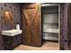 Stylish bathroom with a sliding barn door, modern sink and fixture, and unique wallpaper design at 8294 Wild Timber Dr, Franktown, CO 80116