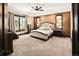 Spacious bedroom featuring a king-size bed, large windows, side tables, and a dresser with carpet flooring at 8294 Wild Timber Dr, Franktown, CO 80116