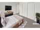 Cozy bedroom with a wooden bed frame, flat-screen TV, and a double-door closet, virtually staged at 1045 Mobile St, Aurora, CO 80011