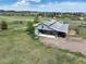 A charming gray barn-style building sits on a vast green acreage with a gray metal roof and an open covered area at 595 W Oak Hill Ln, Castle Rock, CO 80108