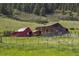 Image of red barn and wooden barn in a grassy field at 15947 S Perry Park Rd, Palmer Lake, CO 80133