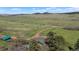 Secluded home nestled in an open green field with distant mountain views and mature tree coverage providing privacy at 15947 S Perry Park Rd, Palmer Lake, CO 80133