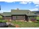 Cozy log cabin with green roof, chimney and surrounded by lush greenery at 15947 S Perry Park Rd, Palmer Lake, CO 80133