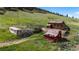 Rustic outbuildings and structures on a grassy lot with fencing and mature trees at 15947 S Perry Park Rd, Palmer Lake, CO 80133