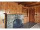 Close-up of stone fireplace with iron grate in a wood-paneled room with built in shelves at 15947 S Perry Park Rd, Palmer Lake, CO 80133