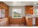 Kitchen area with wood-paneled walls, a window overlooking a view, and vintage cabinetry at 15947 S Perry Park Rd, Palmer Lake, CO 80133