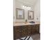 Traditional bathroom featuring dual mirrors, neutral tile, and dark wood cabinets at 6358 S Jackson St, Centennial, CO 80121