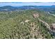 Aerial view showcasing a house surrounded by mature trees and rocky terrain at 30671 Bearcat Trl, Conifer, CO 80433