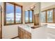 Bathroom featuring a vanity with marble countertops, custom cabinets, and natural lighting from the wide window at 30671 Bearcat Trl, Conifer, CO 80433