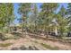 Home with deck blends seamlessly into its natural surroundings with mature trees and natural stone at 30671 Bearcat Trl, Conifer, CO 80433